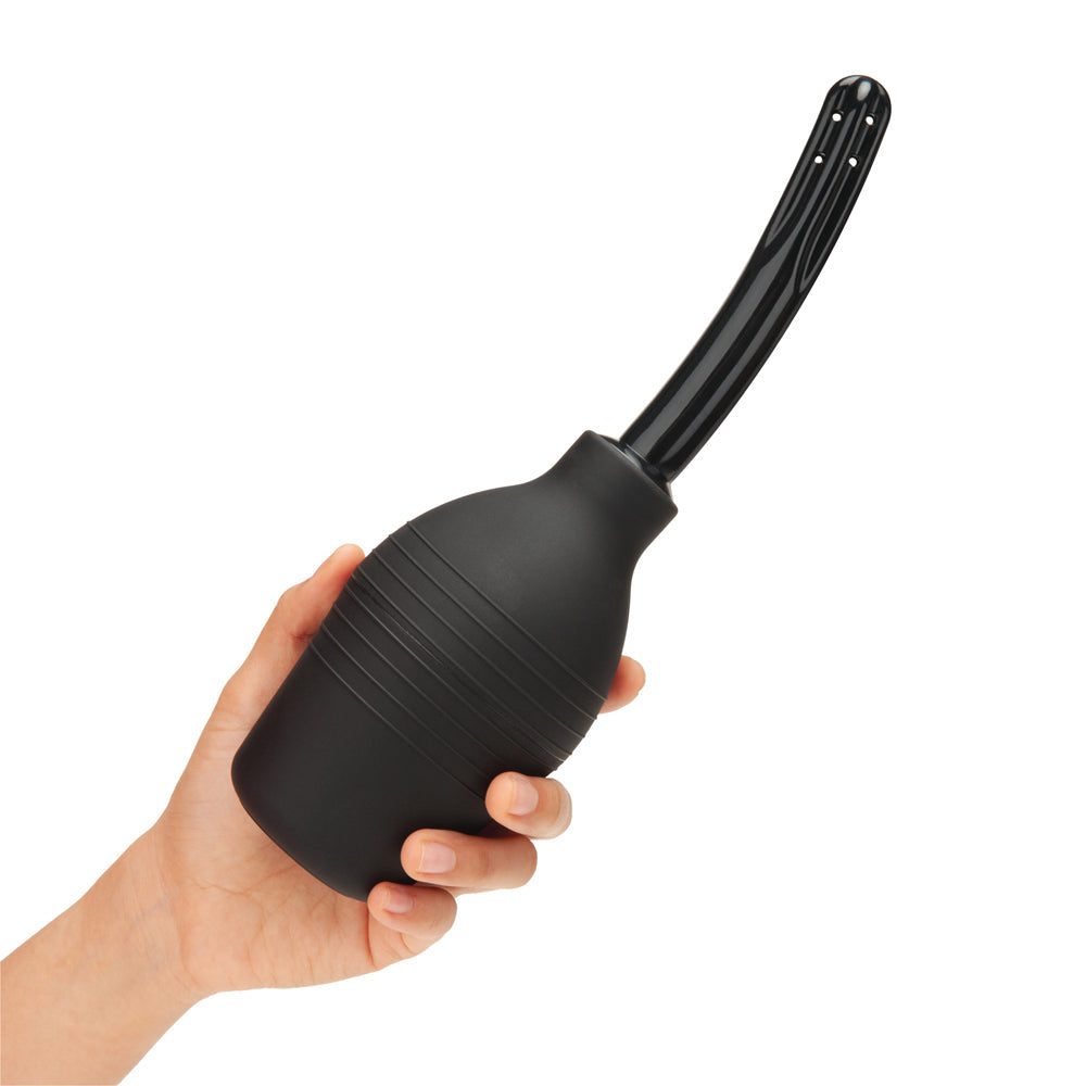 B-Vibe Essentials Enema Douche With Nozzle 310 mL Black in a hand, showcasing its sleek design and usability.