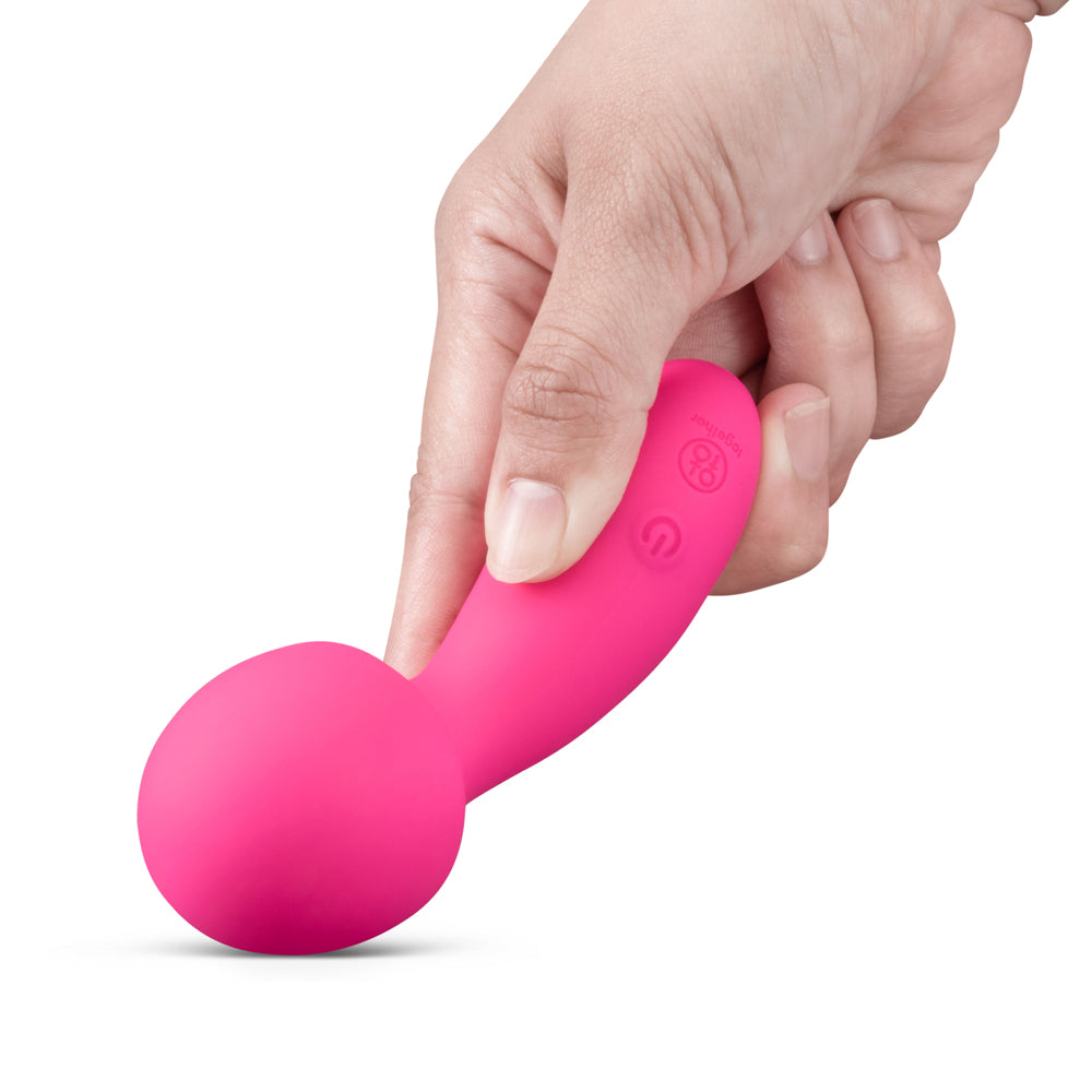Hand holding Together Spark On The Go Mini Wand Vibrator, a compact and playful pink massager.