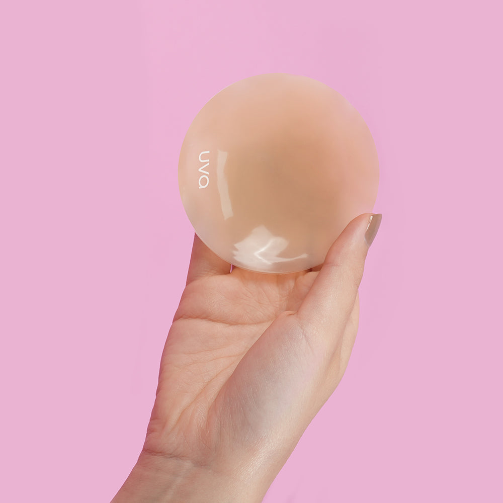 UVA Caramel Non-Adhesive Round Nipple Covers held in hand against a pink background.