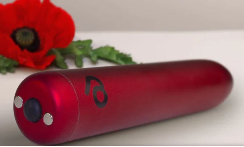Poppy Red Rechargeable Bullet Vibrator resting near a red poppy flower against a light background.