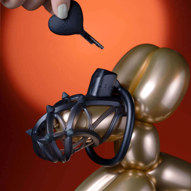 UPKO Caged Beast male chastity device kit displayed on a balloon figure with a black heart-shaped key, showcasing sleek design.