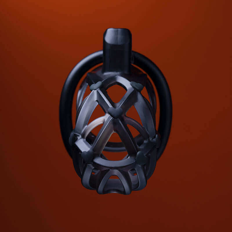 UPKO Caged Beast Male Chastity Device Kit in black against an orange background, showcasing its unique design and structure.