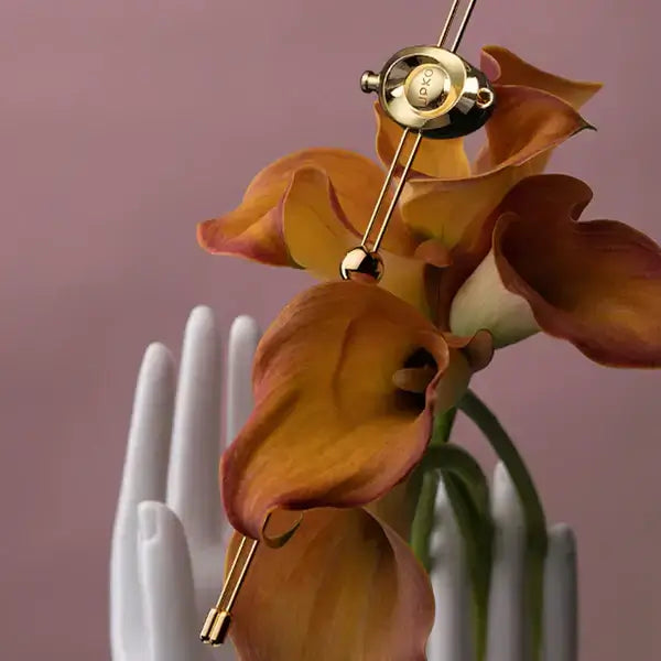 Luxurious UPKO Double Bar Vibration Nipple Clamp on elegant orange flowers with artistic background.