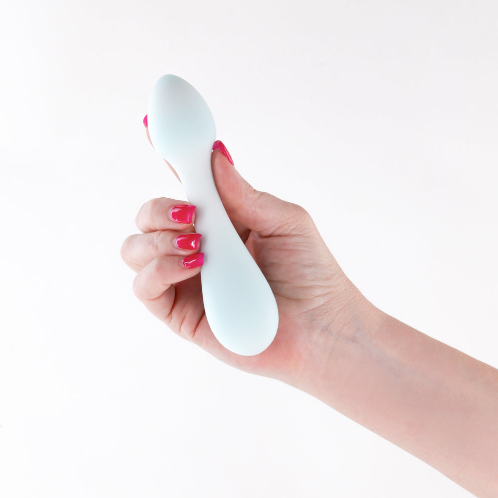 NS Novelties Pure Hope Silicone Clitoral Vibrator Blue held in a hand with colorful nails.