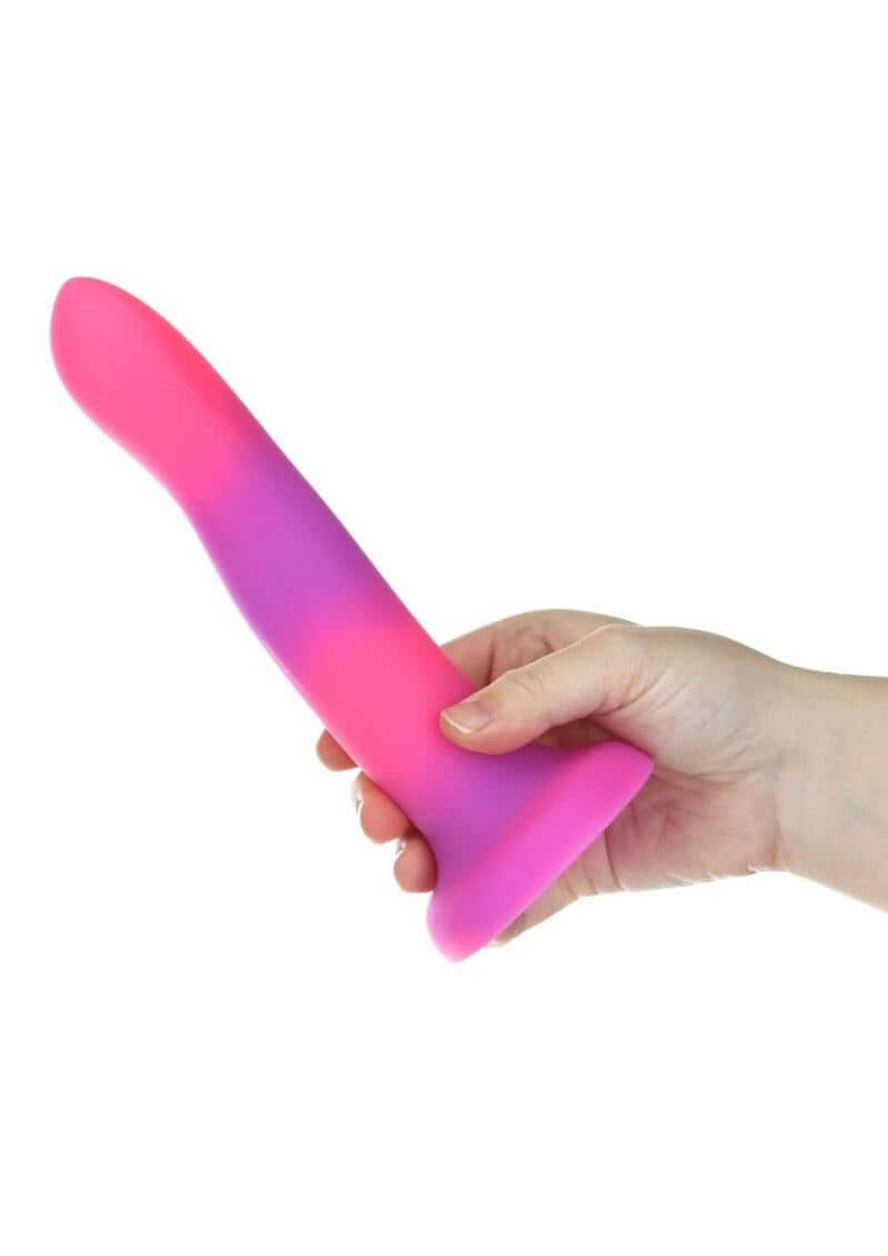 Addiction Rave Silicone Glow In The Dark Dildo 8 inch Pink Purple held in hand, showcasing vibrant colors and design.