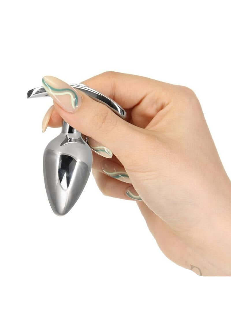 A person holding the Pillow Talk Sneaky Luxurious Stainless Steel Anal Plug, showcasing its sleek design and premium material.