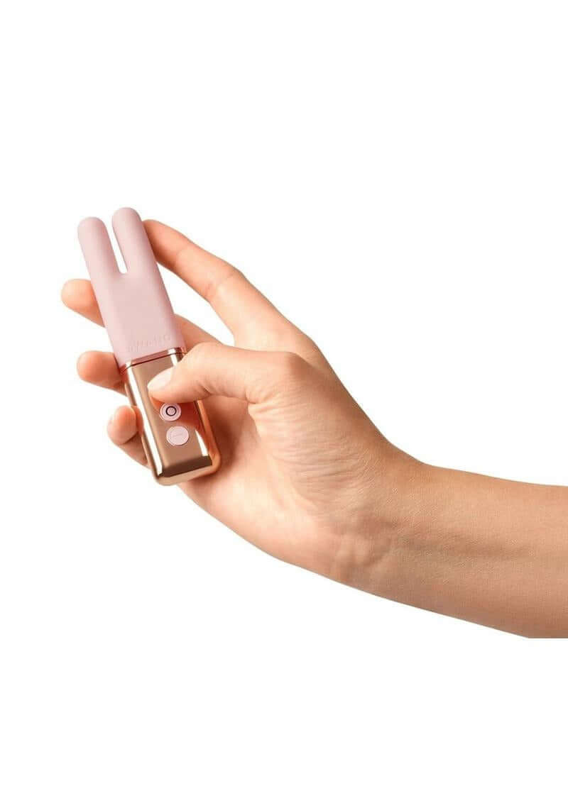 Hand holding Le Wand Deux Silicone Clitoral Vibrator Rose Gold, showcasing its elegant design and easy controls.
