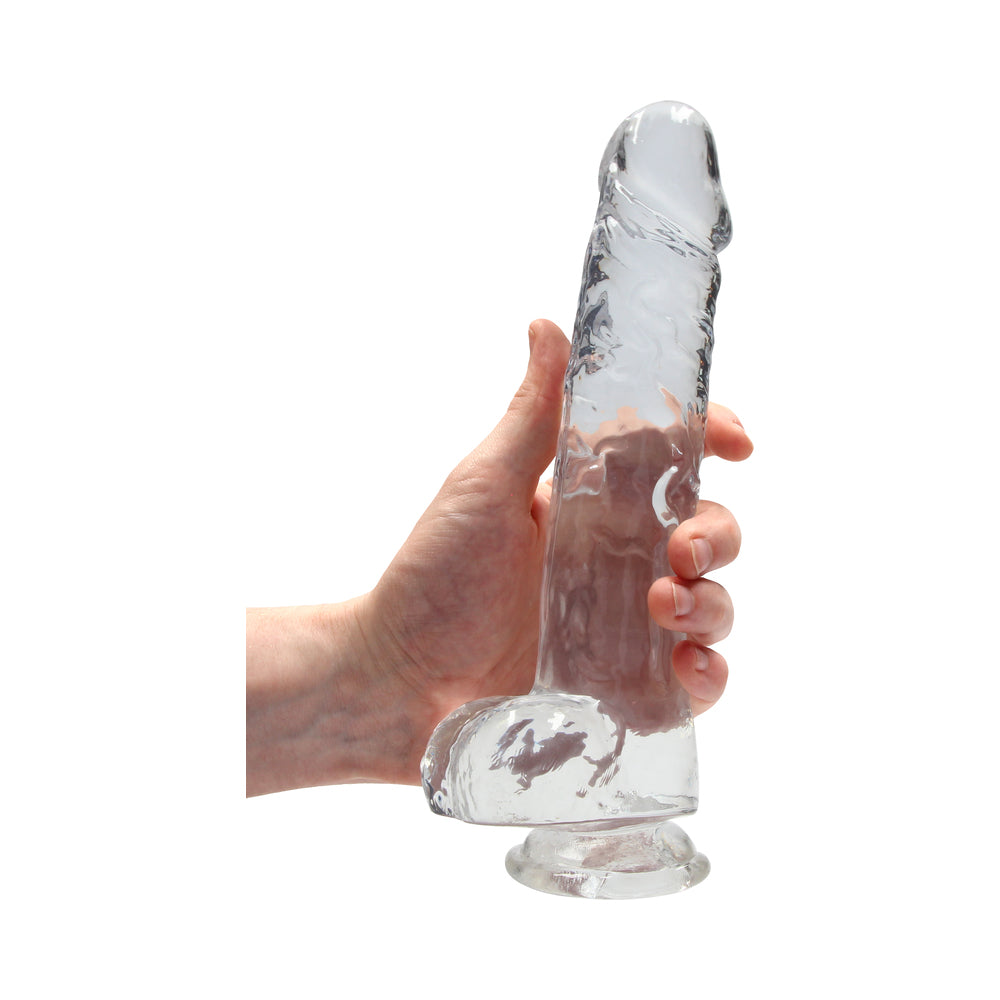 RealRock Crystal Clear Realistic 9 inch Dildo With Balls Clear held in hand showcasing its lifelike design and transparency.