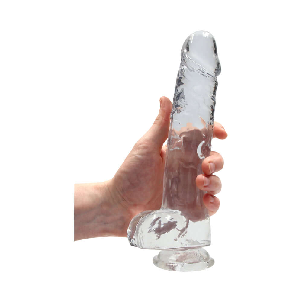 RealRock Crystal Clear Realistic 9 inch Dildo With Balls Clear held in hand showcasing its lifelike design and transparency.