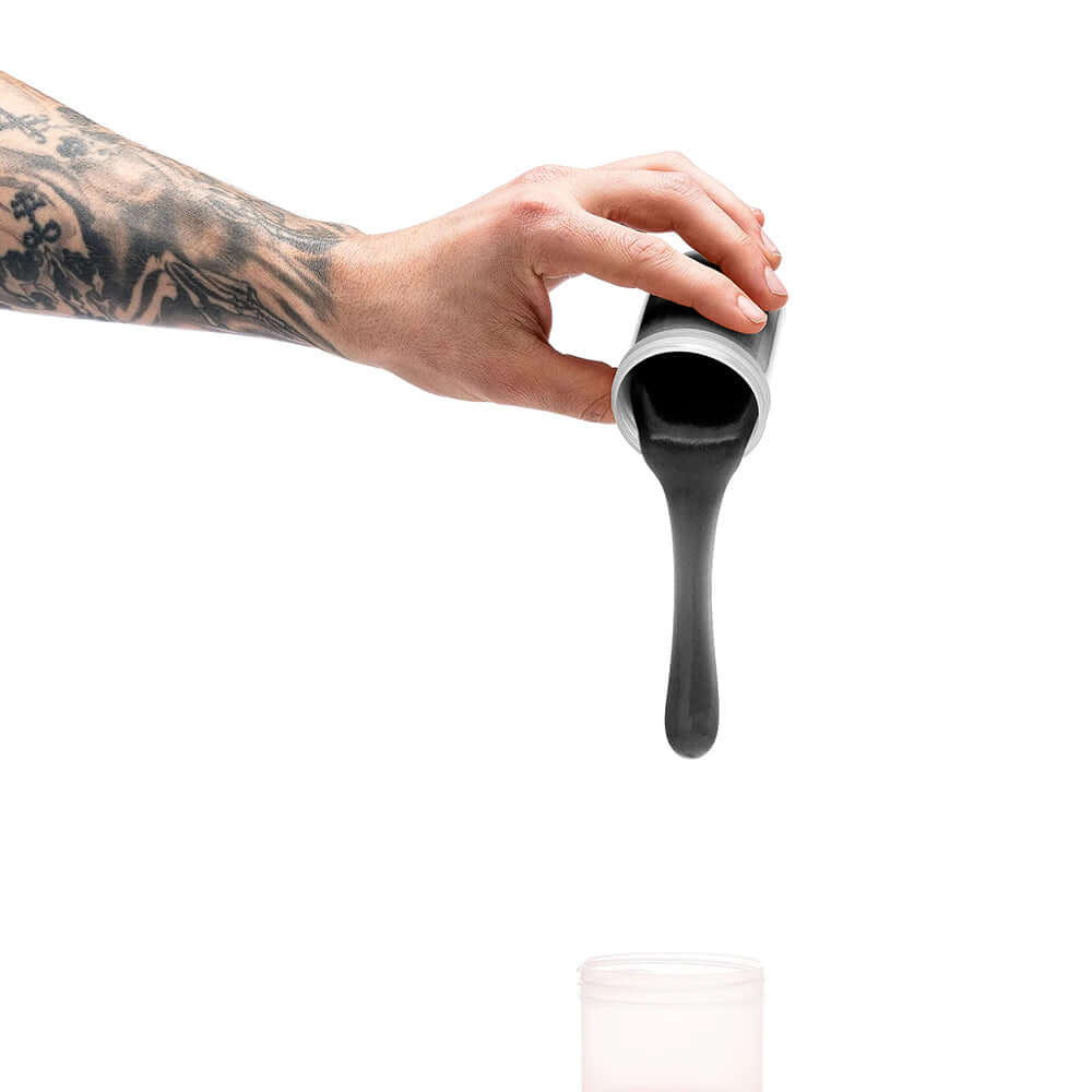 A hand pouring black silicone from a container, demonstrating usage of Clone-a-willy Silicone Refill Jet Black.