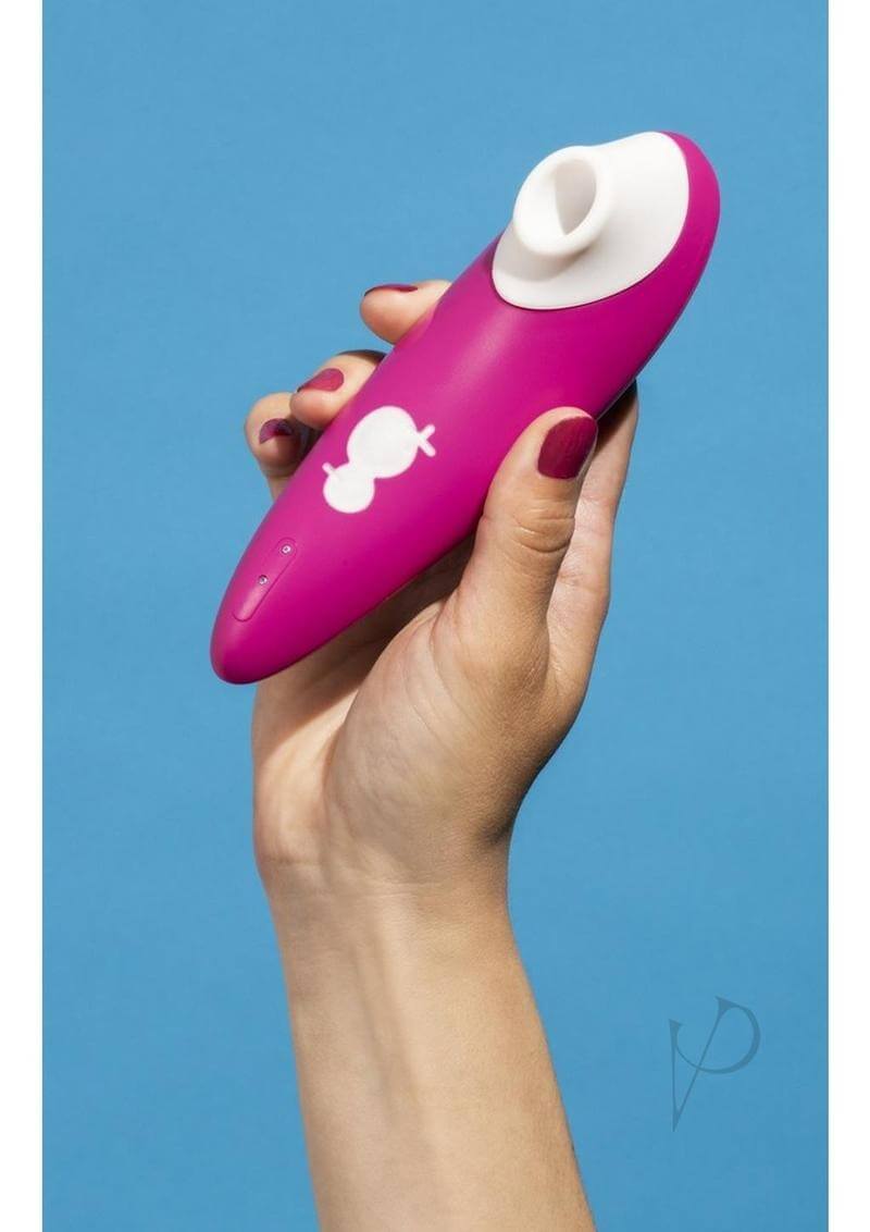 Hand holding the Romp Shine Clitoral Air Stimulator Pink against a blue background.