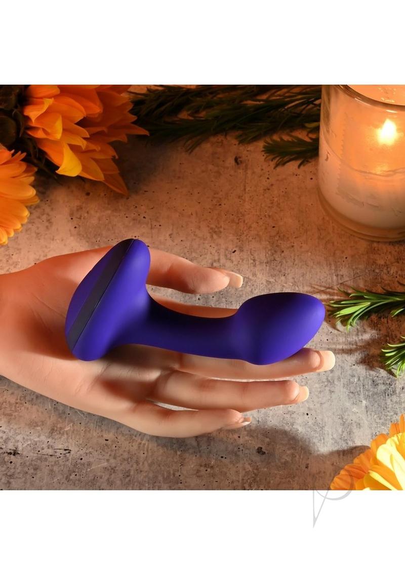 Gender X Anybody's Plug Silicone Vibrating Butt Plug Blue resting on a hand with flowers and a candle.