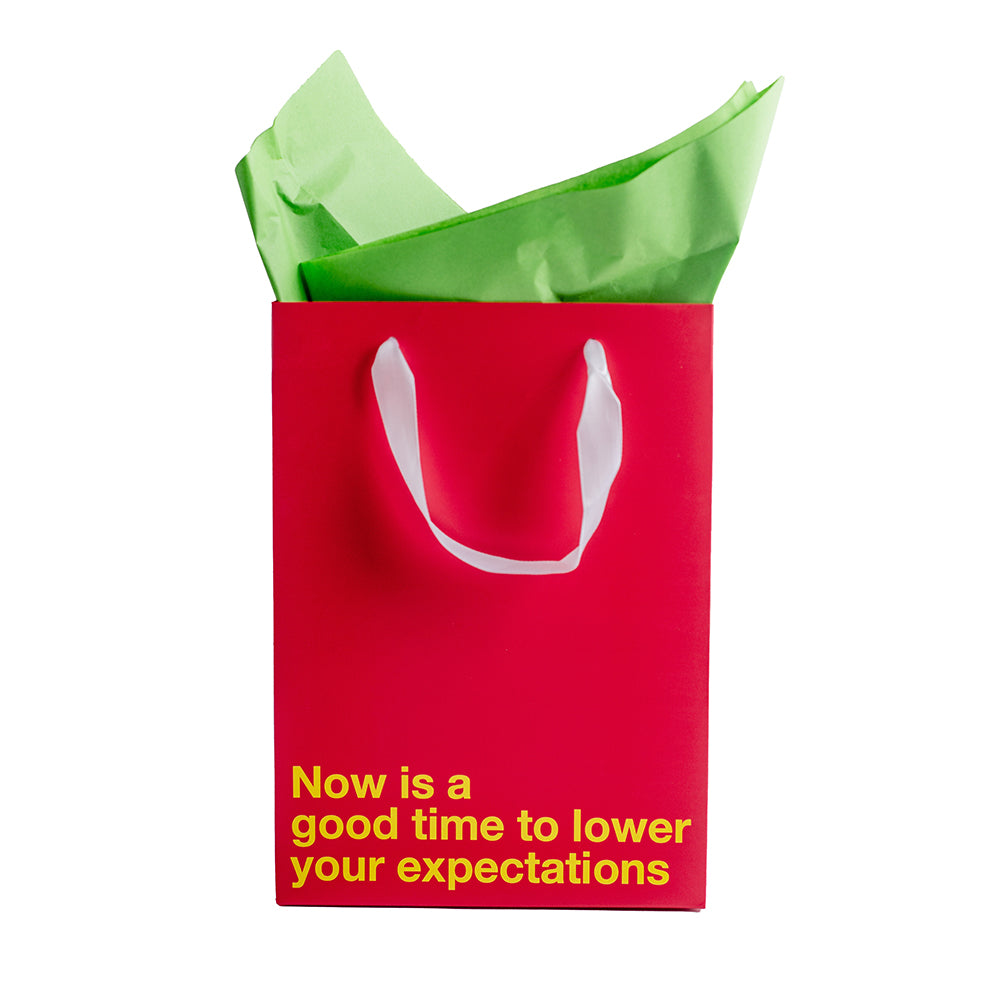 Lower Your Expectations Color Gift Bag Red featuring bold message and tissue paper.