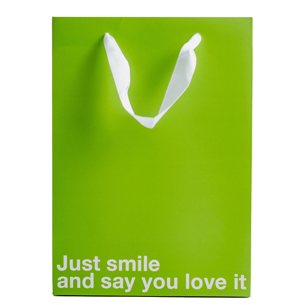 Just Smile & Say You Love It Color Gift Bag Green on display with white text for gift giving humor.