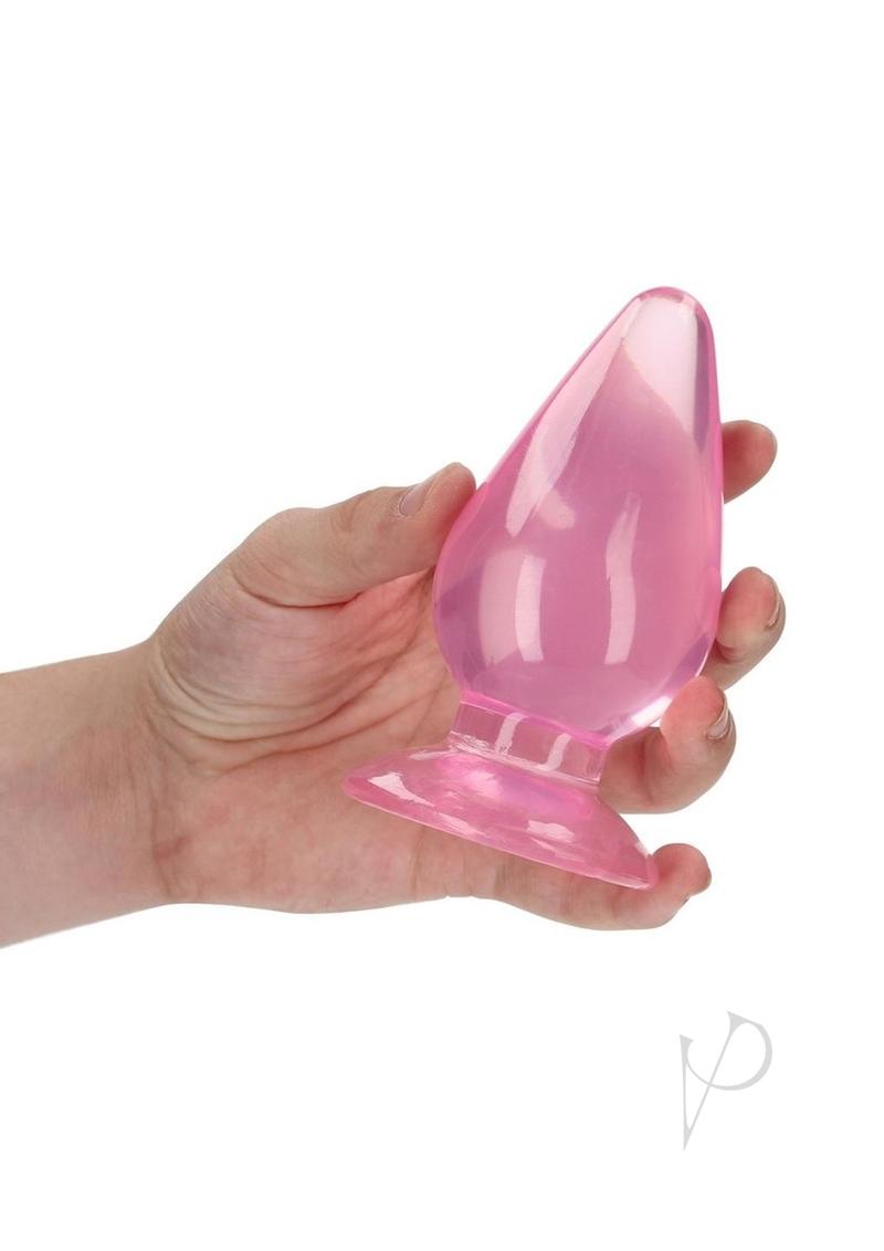 Hand holding RealRock Crystal Clear Anal Plug 4.5 Inch Pink showcasing its sleek design.