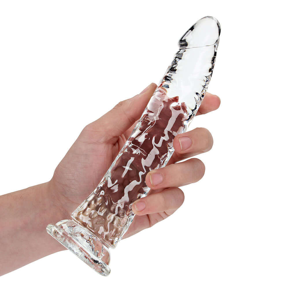 RealRock Crystal Clear Slim 8 inches Dildo Clear held in hand, showcasing its sleek transparent design and smooth surface.