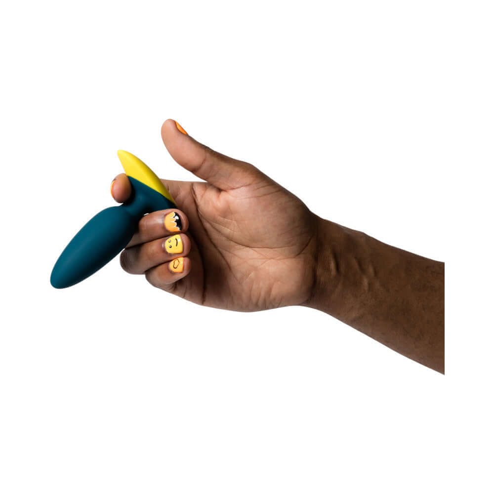 Hand holding ROMP Bass Rechargeable Silicone Vibrating Anal Plug Dark Green with vibrant yellow accent.