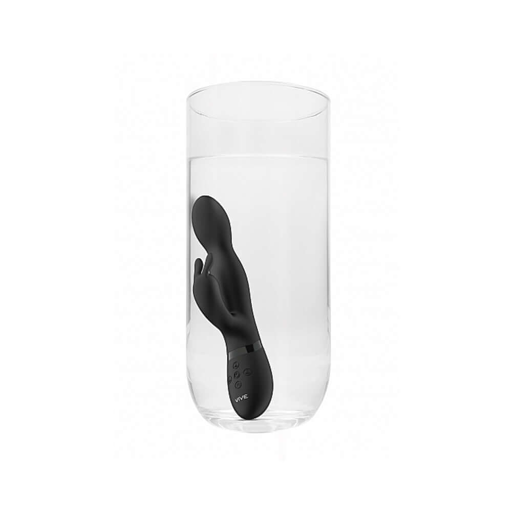 VIVE NIVA Rechargeable 360 Rotating Rabbit Vibrator Black submerged in water in a glass