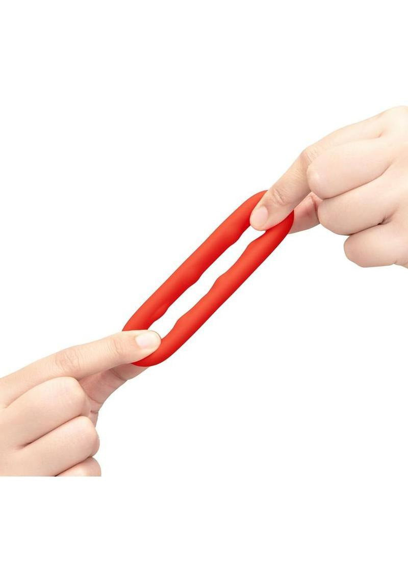 B-Vibe Flex Ring Grip Silicone Cock Ring Red being stretched between two hands, showcasing its flexibility and durability.