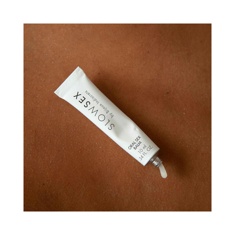 Bijoux Indiscrets Slow Sex Oral Sex Balm 0.34 Oz tube on a textured brown surface.