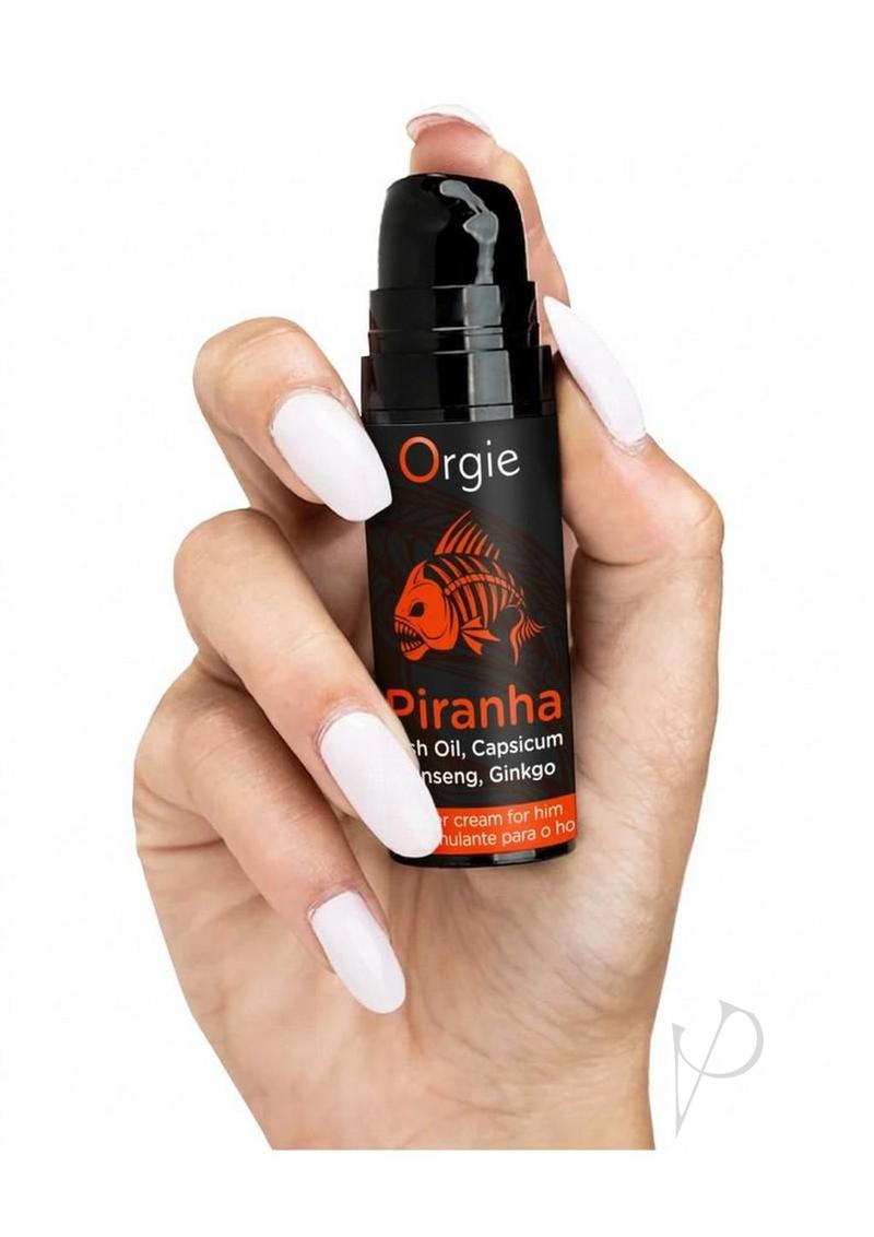 Orgie Piranha Power Cream for Him 0.5 Oz bottle held in a hand with white nails.