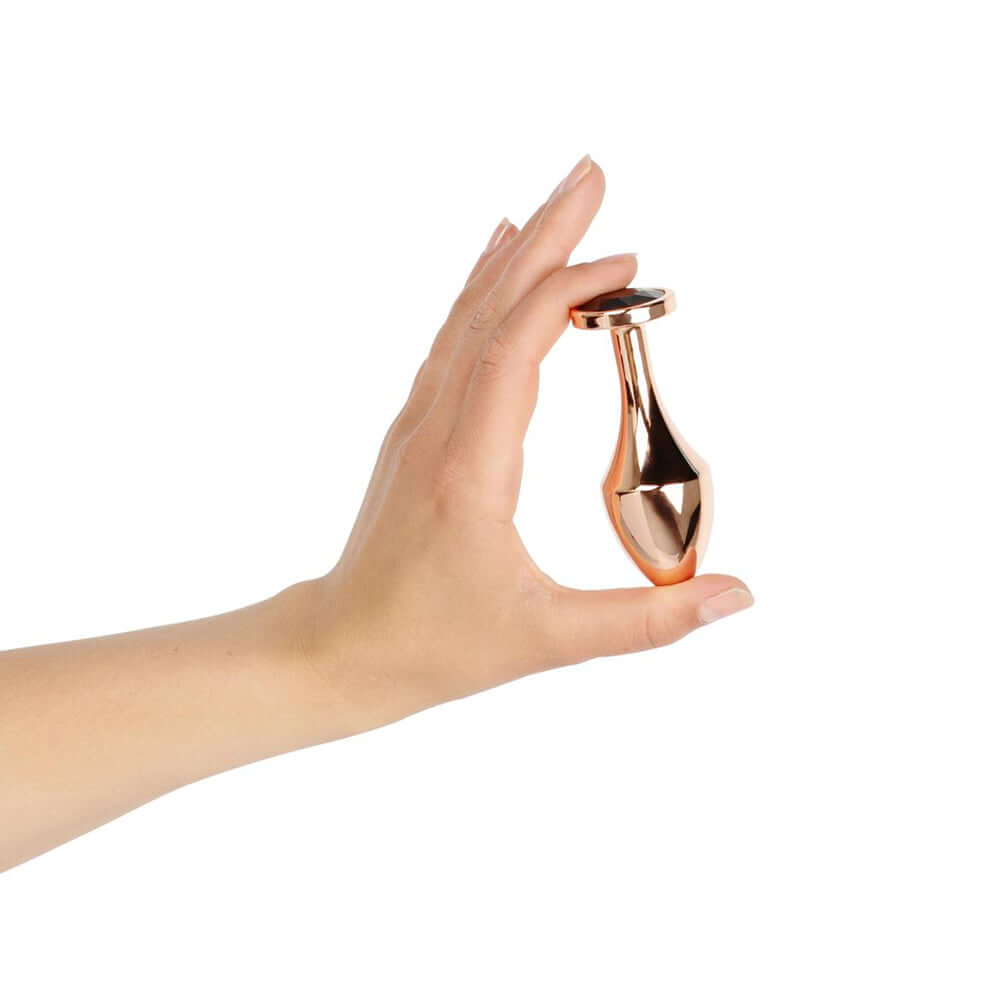 Hand holding Rosy Gold Nouveau Butt Plug, showcasing its luxurious design and shiny aluminum finish.