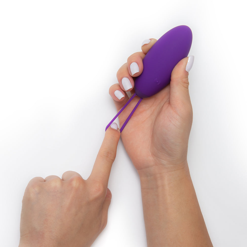 Wellness Imara Vibrating Egg with Remote Purple held in hand, showcasing its ergonomic design and texture.