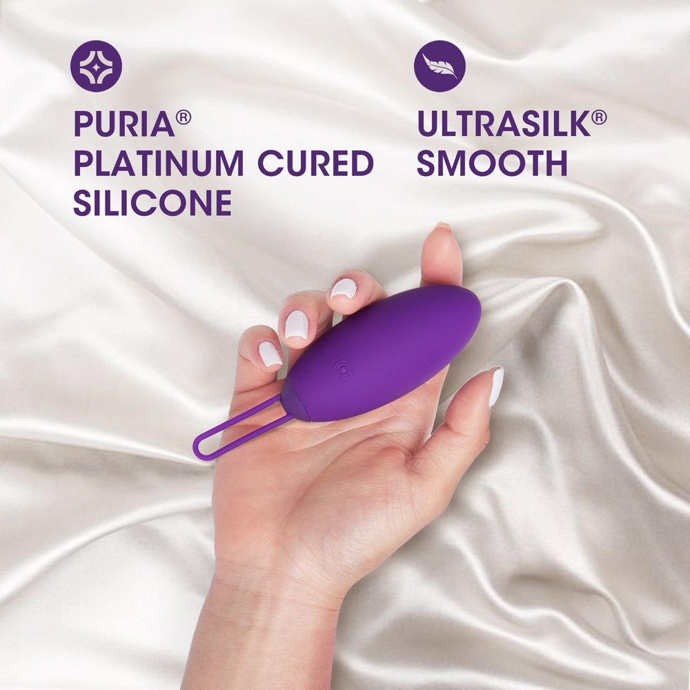 Wellness Imara Vibrating Egg with Remote Purple in a hand, showcasing Puria platinum cured silicone and UltraSilk smooth texture.