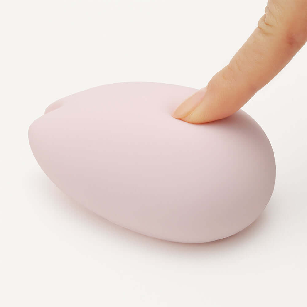Close-up of the Tenga iroha SAKURA Massager with a finger gently pressing its soft surface.