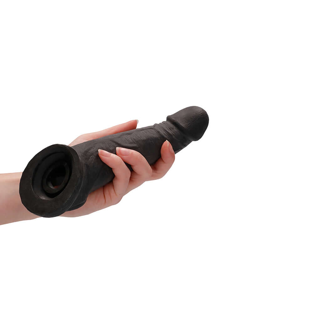 RealRock Skin 8 inches Penis Extender Sling Black held in hand, showcasing its realistic design and texture.