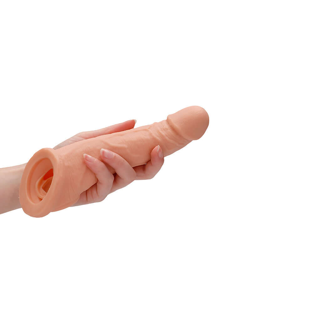 RealRock Skin 8 inches Penis Extender Sling Beige held in a hand, showcasing its realistic design and lifelike texture.