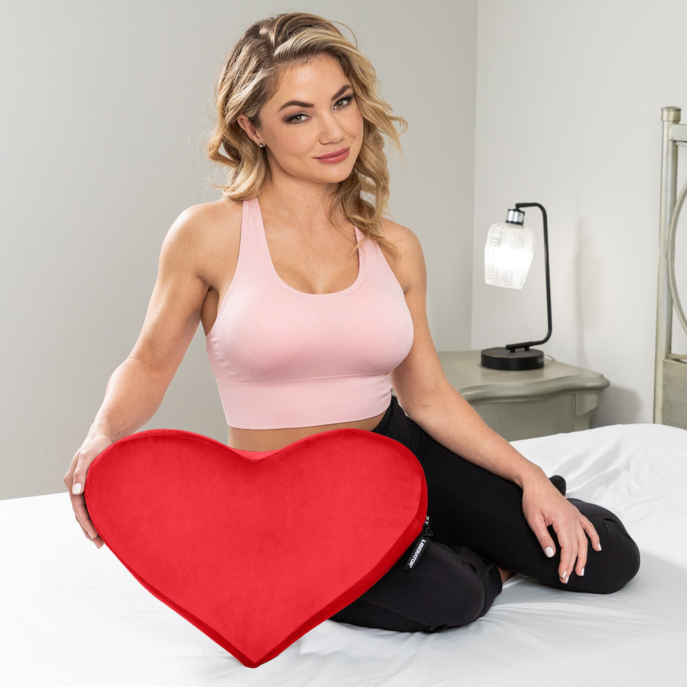 Woman sitting with red Liberator Heart Wedge Red cushion, showcasing passion and comfort for enhanced lovemaking.