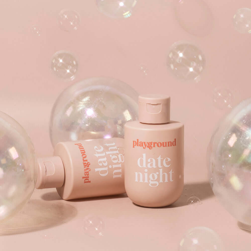 Playground Date Night Water-Based Personal Lubricant 3.7 Oz bottle surrounded by bubbles on a soft pink background.