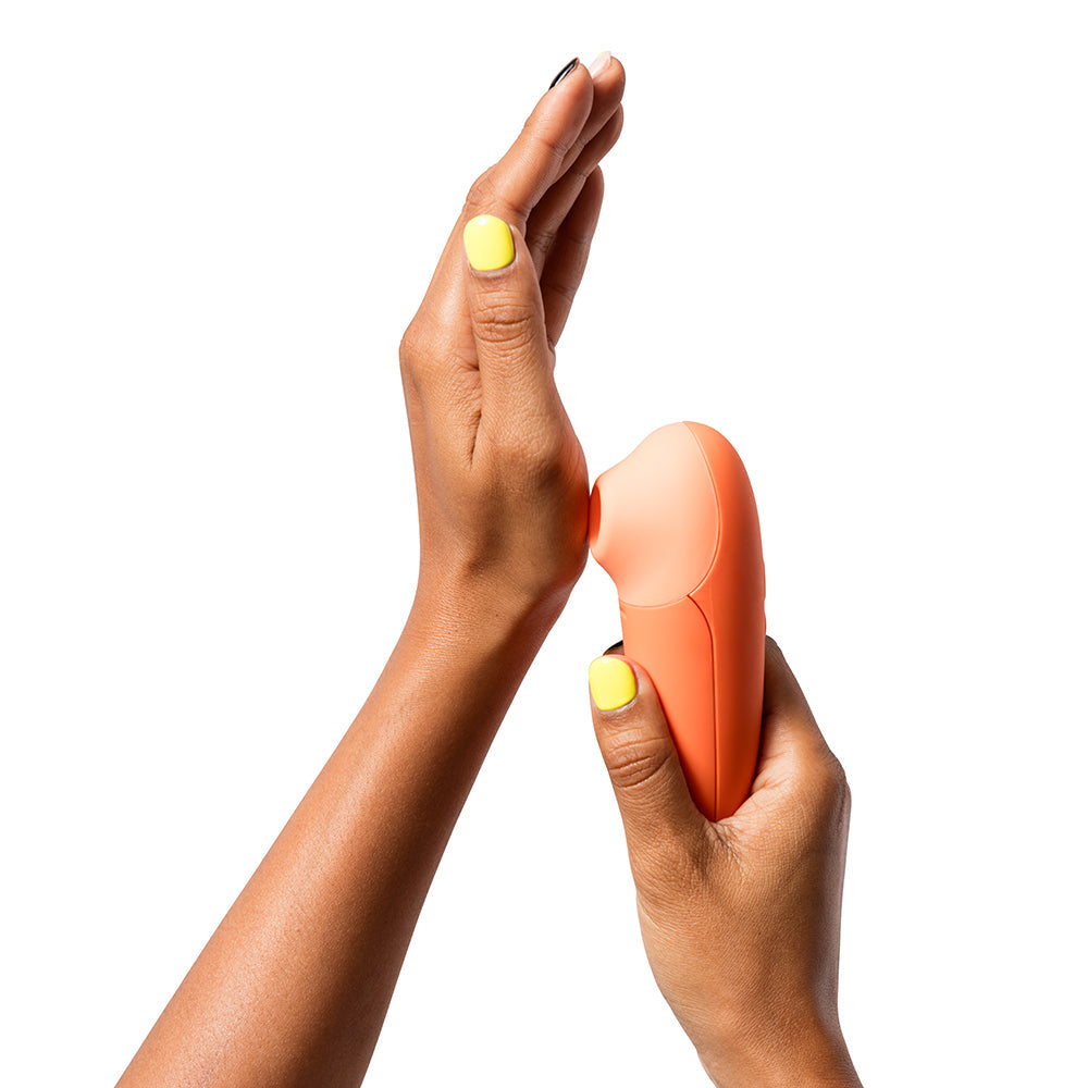 ROMP Switch X Clitoral Stimulator held in hands demonstrating its compact design and soft silicone head.
