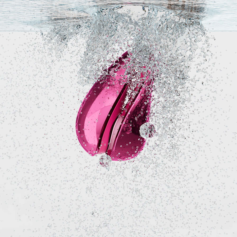 Womanizer x Iggy Azalea Liberty 2 Special Edition Metal Pink submerged in water with bubbles.