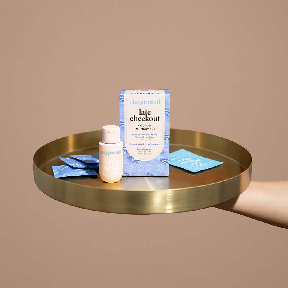 Playground Late Checkout Couples Intimacy Set displayed on a golden tray with blue packets and sensual care products.
