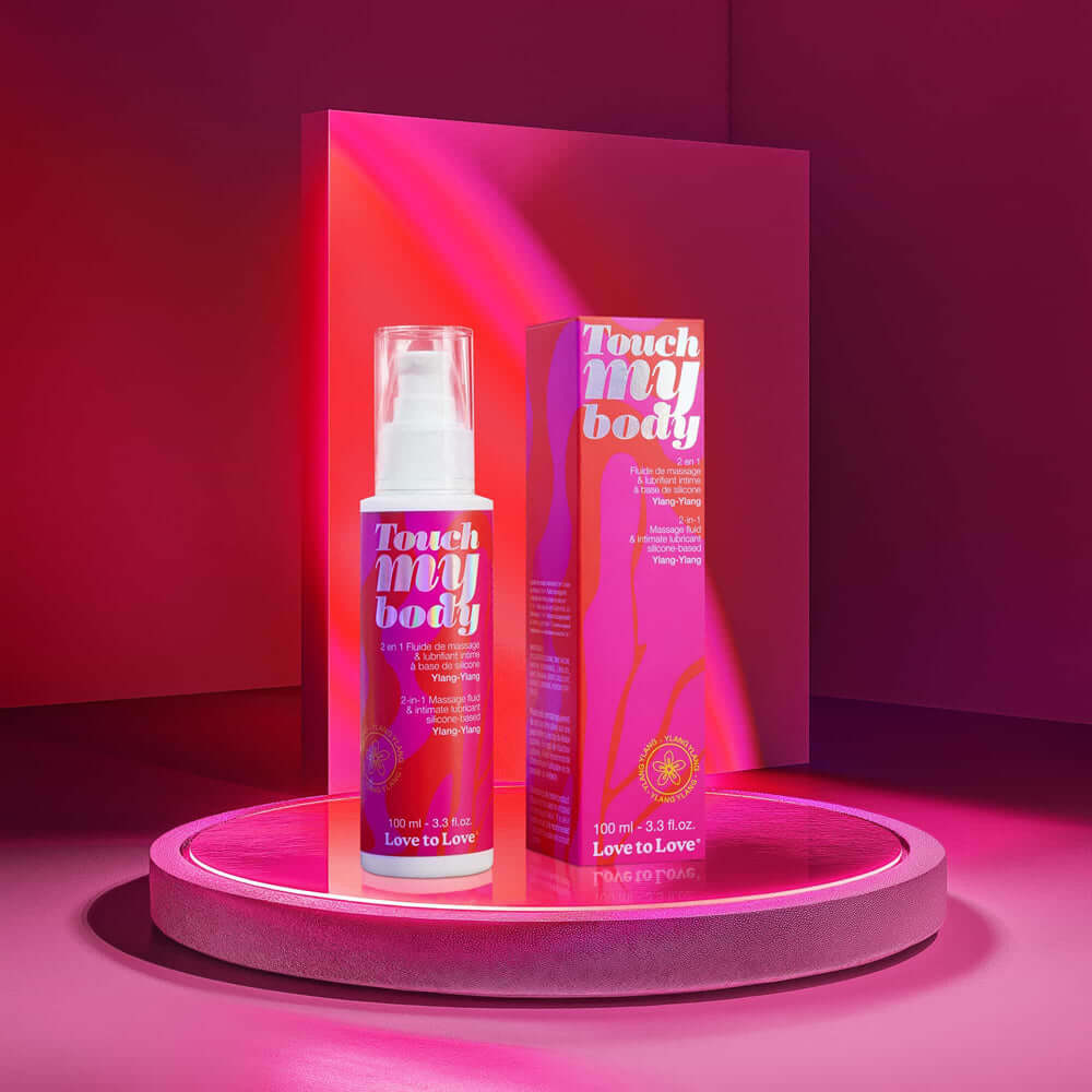 Touch My Body 2-in-1 Massage Fluid & Intimate Lubricant Ylang-Ylang 3.3 Oz displayed on a neon pink shelf.