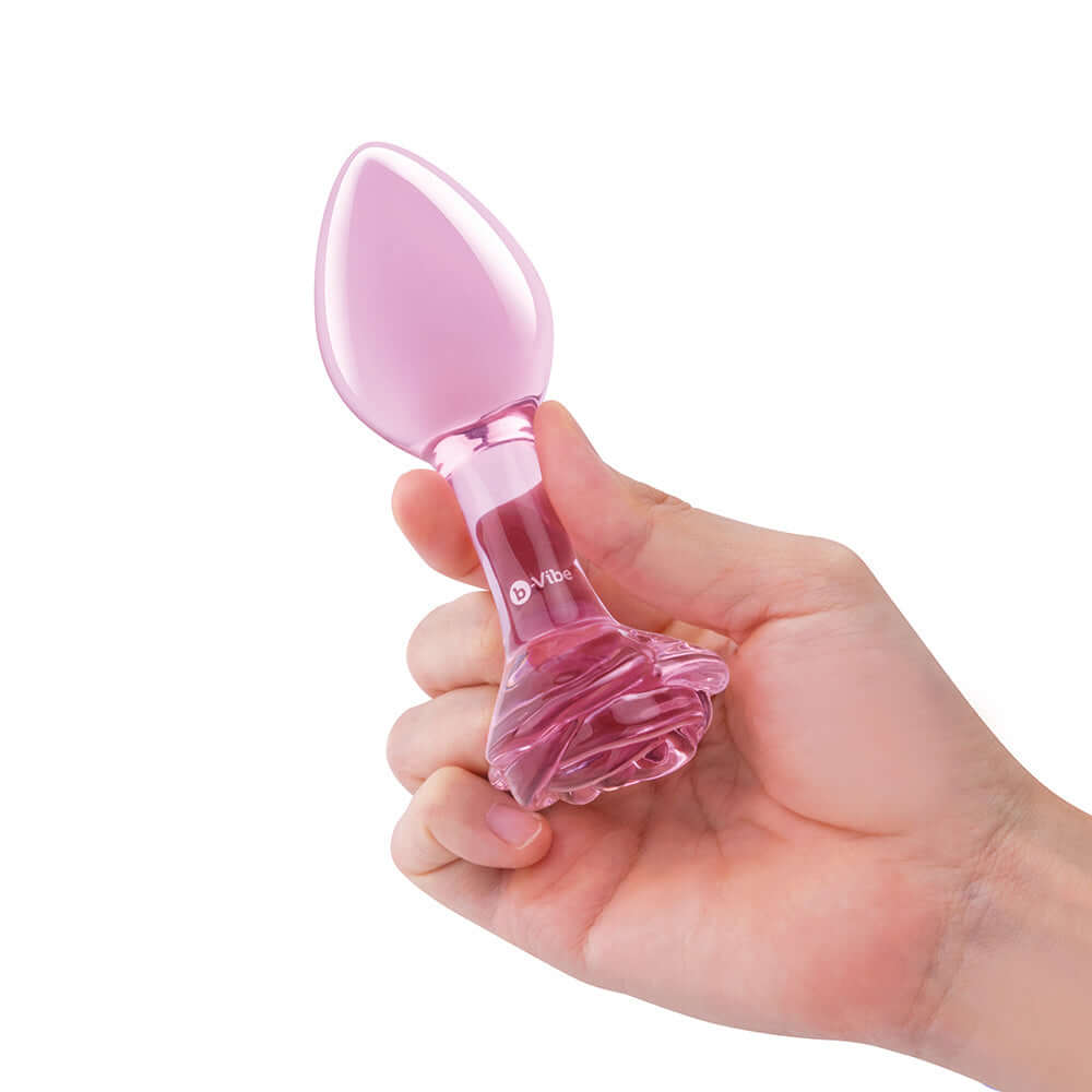 b-Vibe Glass Pink Roses Training Plug Set held in hand, featuring a sleek pink design and rose-detailed base.