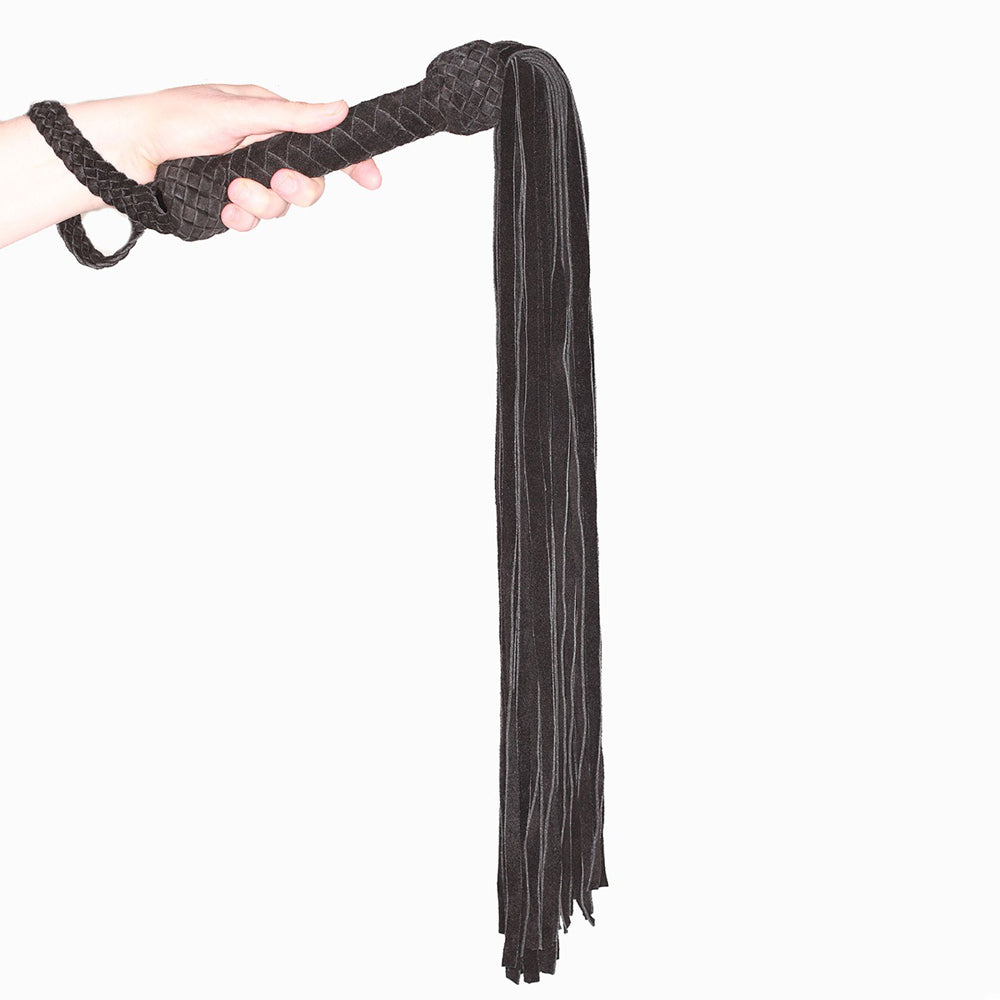 Prowler Red Leather Suede Flogger Black in hand, featuring a suede-wrapped handle and long tasseled strands.