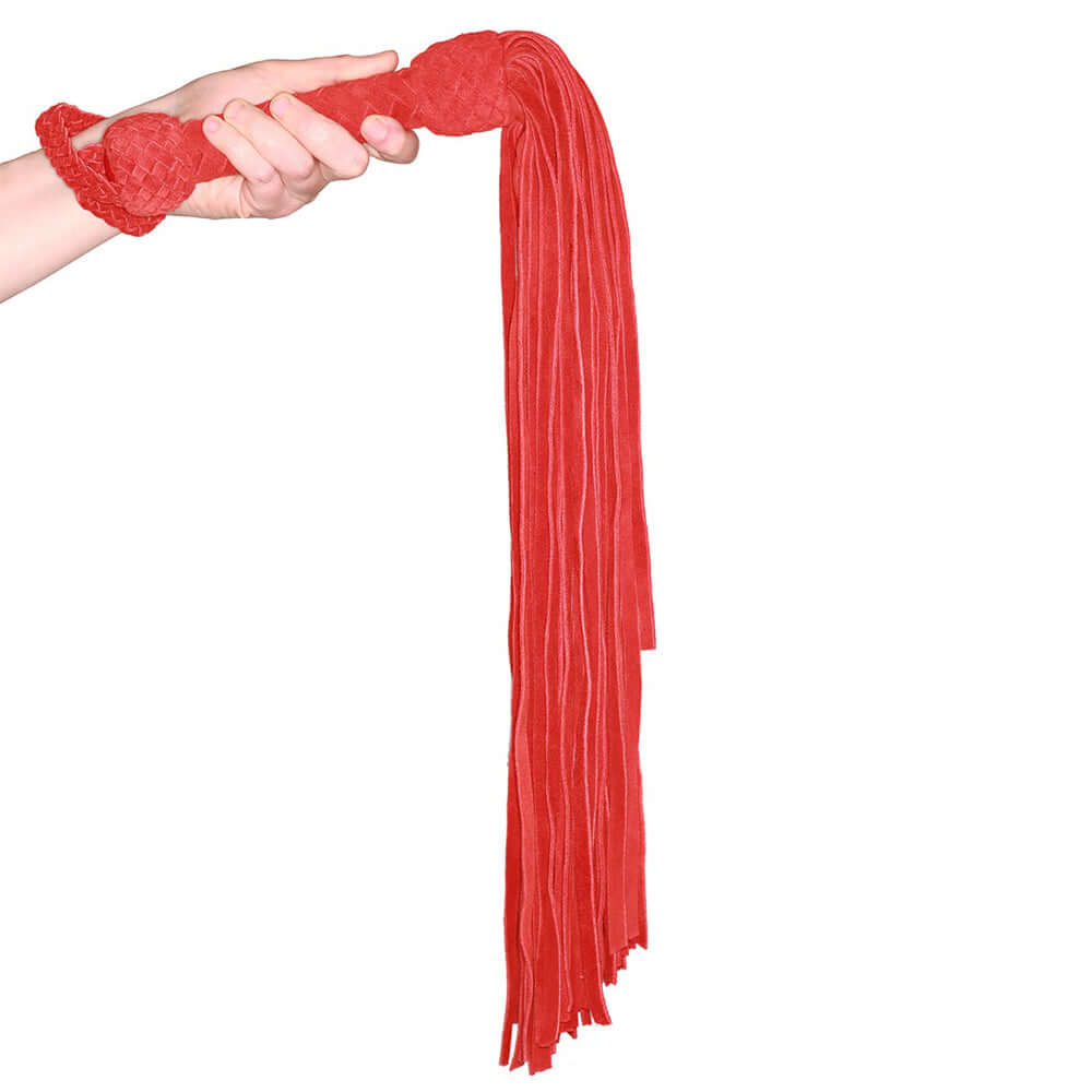 Prowler Red Leather Suede Flogger Red held by a hand, showcasing its tassels and suede-wrapped handle.