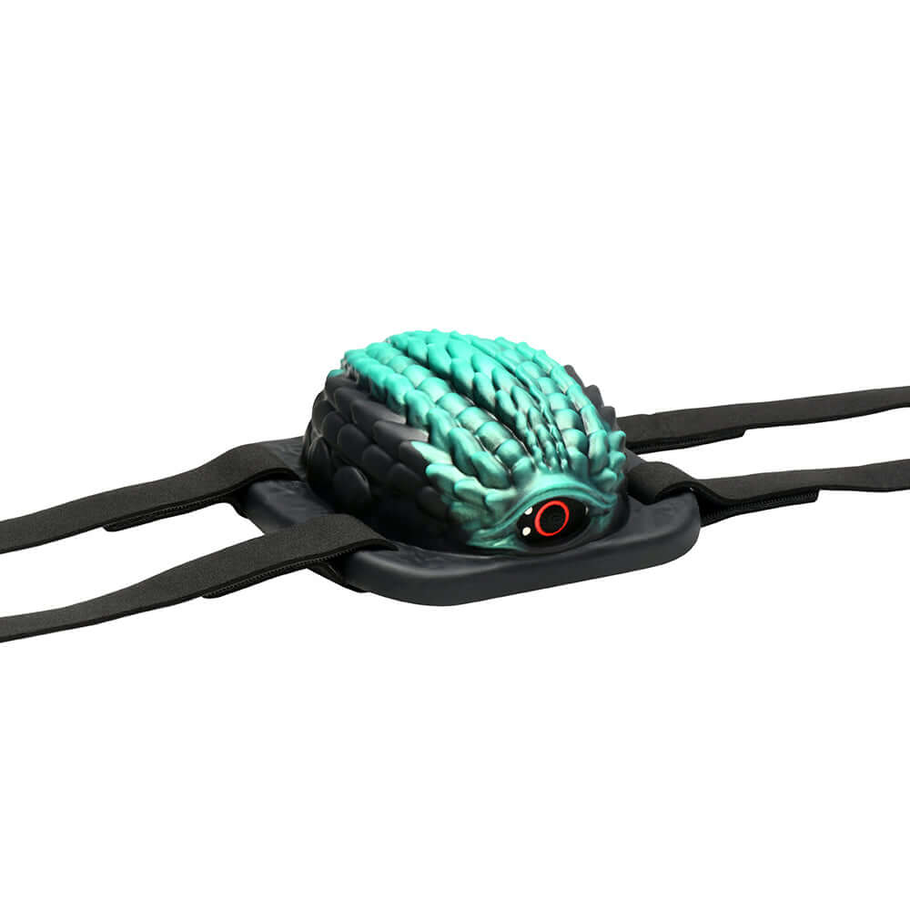 Creature Cocks Dragon Vibrating Silicone Grinder on a black base with textured blue-green surface and straps.