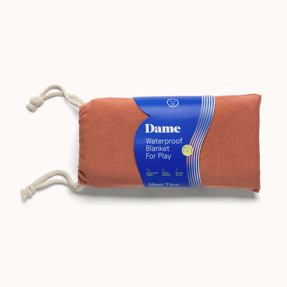 Dame Thro Waterproof Sex Blanket Copper rolled up with tags, designed for comfort and protection during intimate moments.