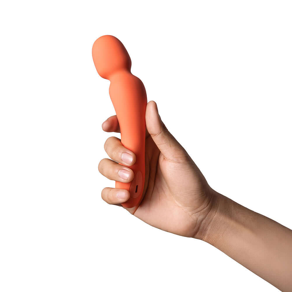 Dame Min Mini Wand Vibrator Papaya held in hand showcasing its compact design and vibrant color.