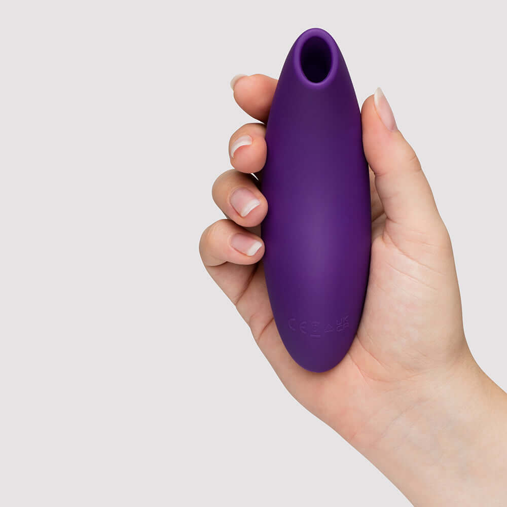 We-Vibe Melt 2 Pleasure Air Clitoral Stimulator Purple held in hand, showcasing its ergonomic design.