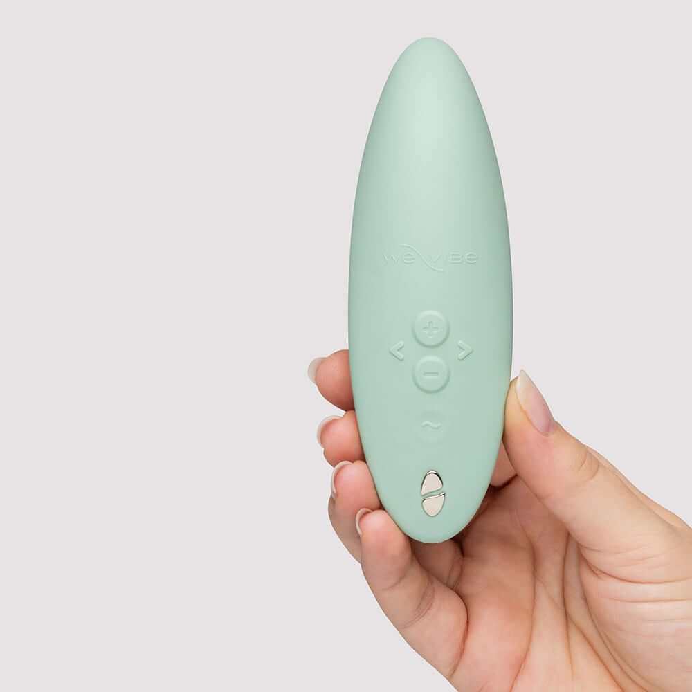 We-Vibe Melt 2 Pleasure Air Clitoral Stimulator Sage held in hand, showcasing its sleek design and buttons.