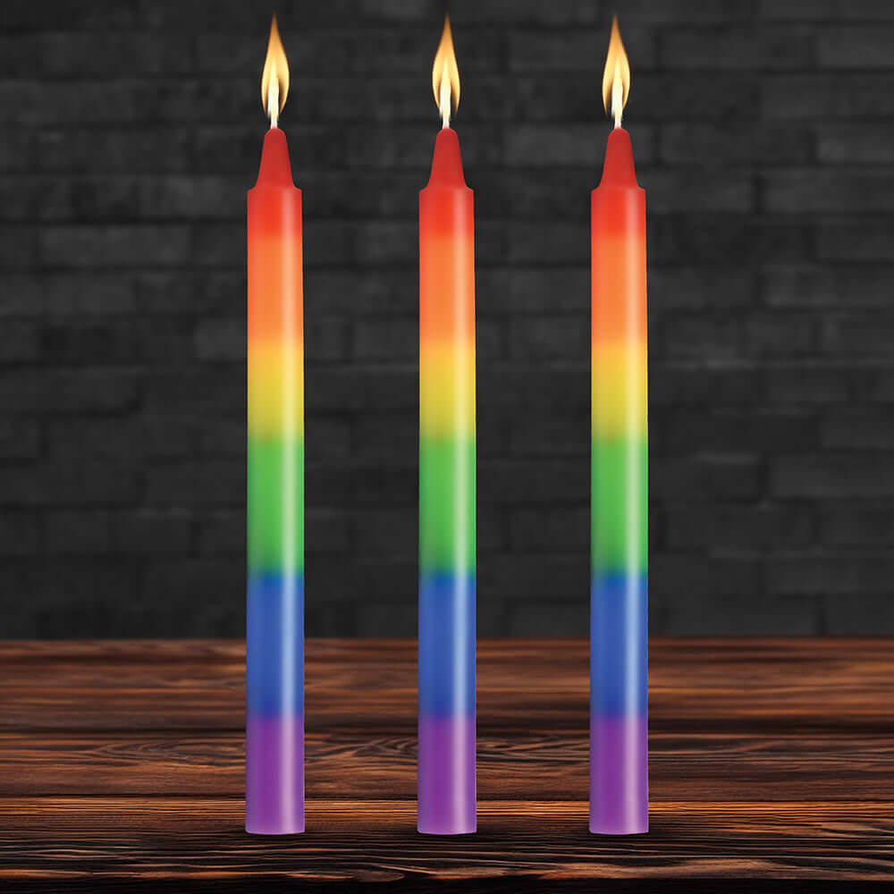 Master Series Pride Candles Rainbow Drip Candle Set of 3 with vibrant rainbow colors and flames on a wooden table.