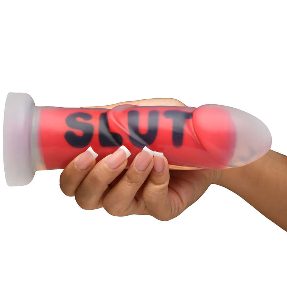 Person holding the Master Series SLUT Silicone Dildo featuring bold text and a premium design for intimacy.