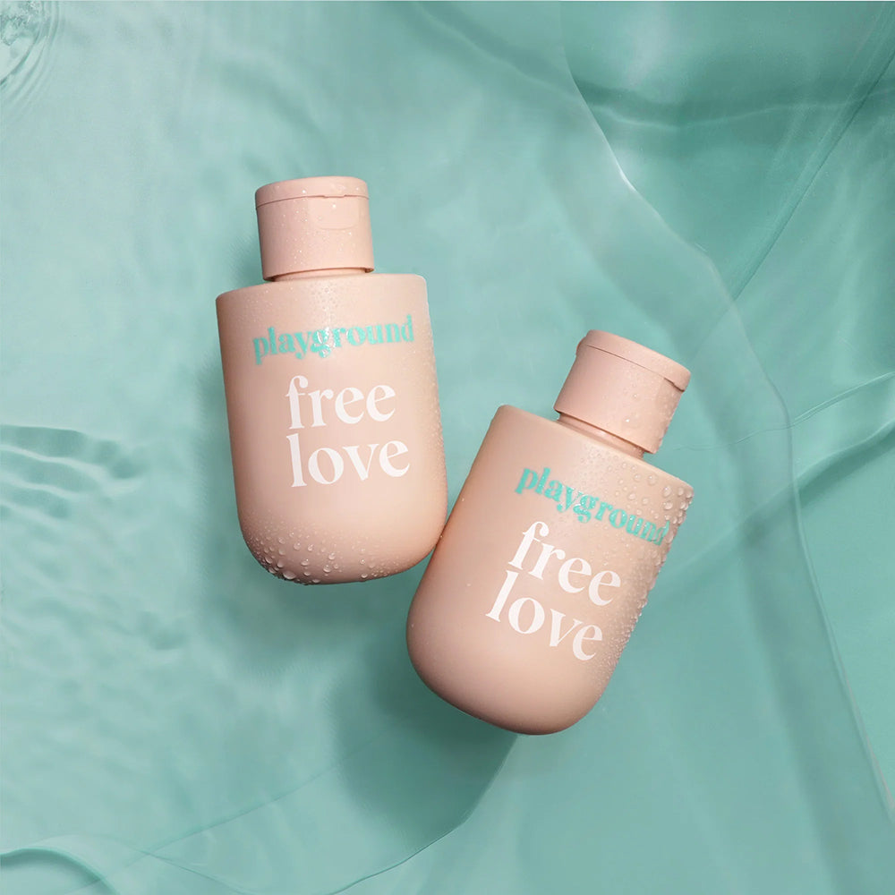 Playground Free Love Water-Based Personal Lubricant 3.7 Oz bottles on a teal background.