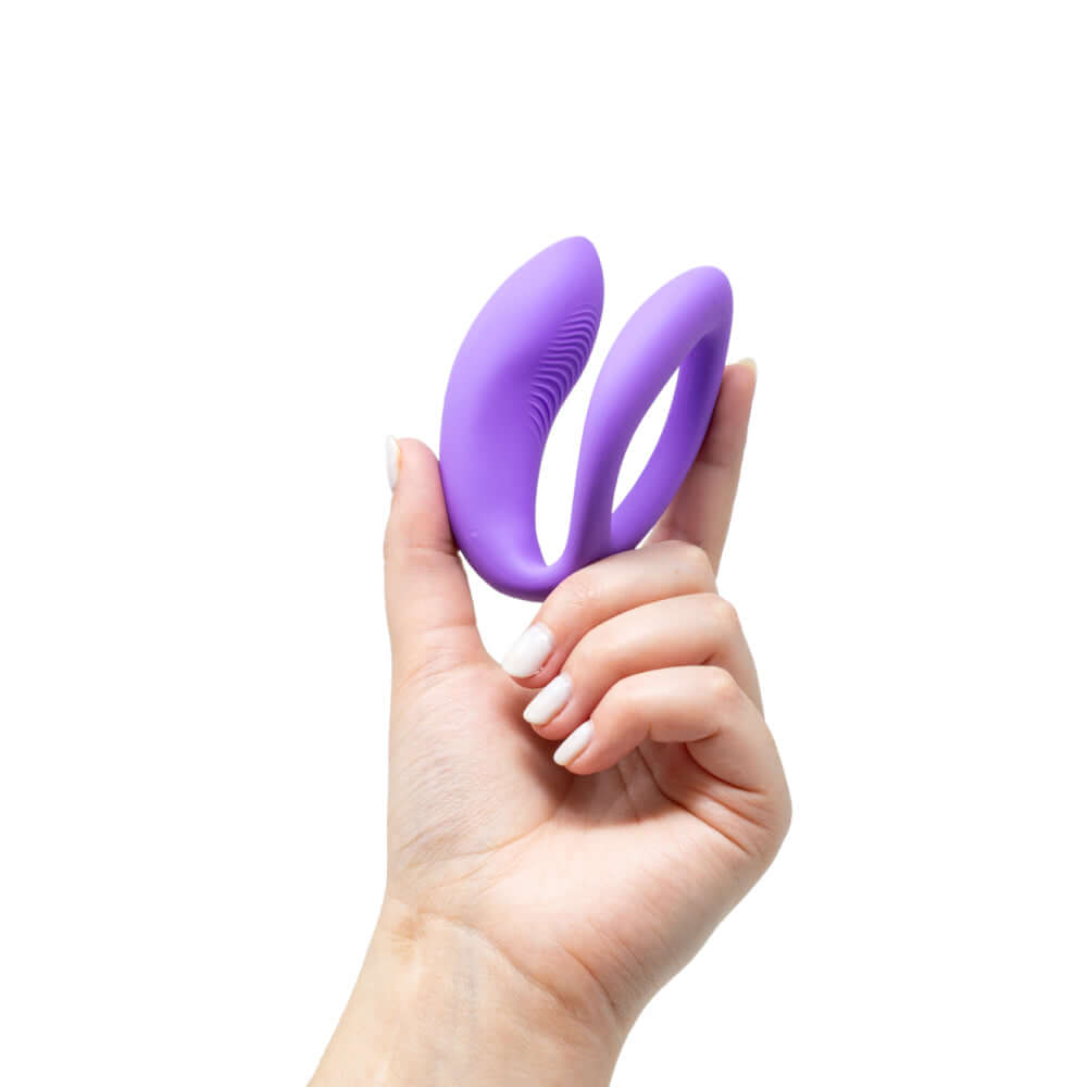 We-Vibe Sync O Vibrator Light Purple held in hand, showcasing its unique design for couples' enjoyment.