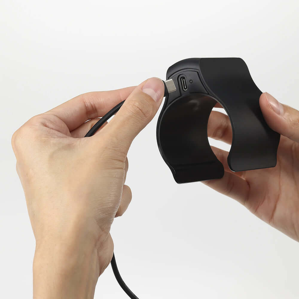 Person connecting a charging cable to the Tenga Cup Vibrator for convenient recharging.